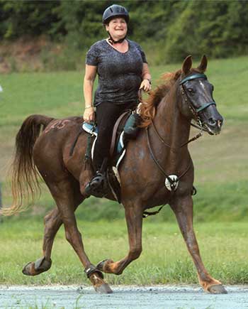A woman riding on the back of a brown horse.