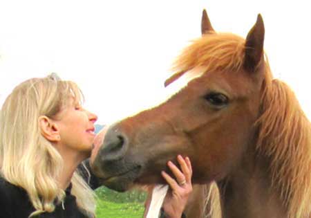 A woman is petting the face of a horse.