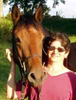 A woman standing next to a horse in the grass.